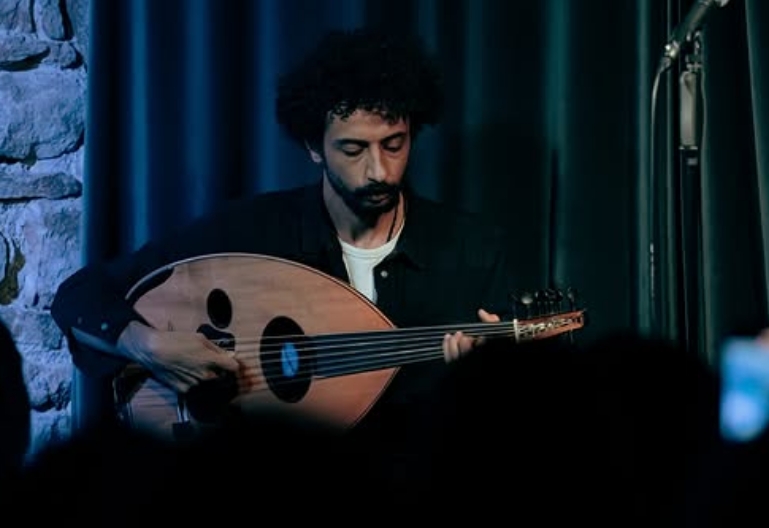An oud player performing on stage during A Trip to Cairo at Carlitos Comedy Club